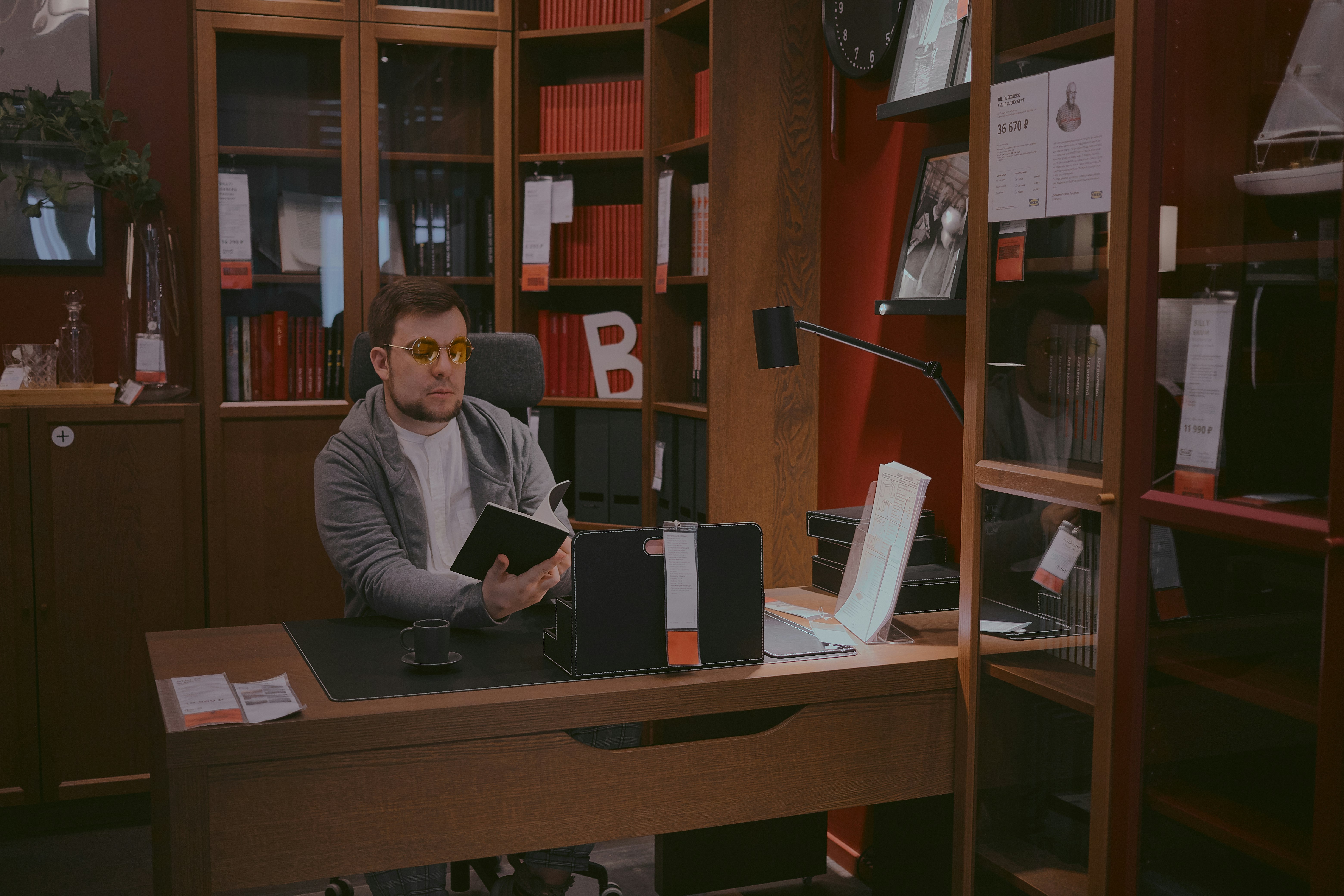 man in gray sweater sitting beside brown wooden desk